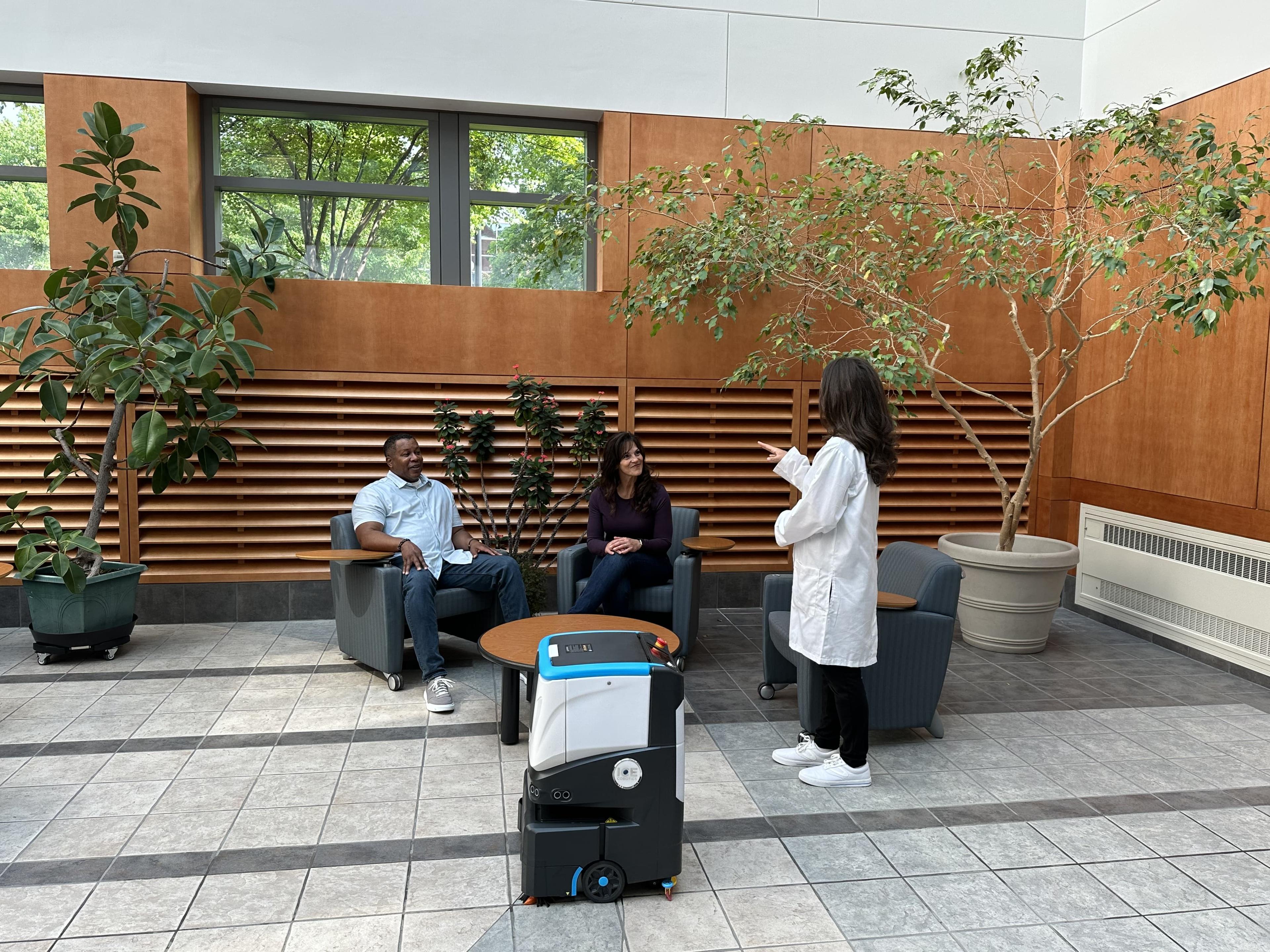 ICE Cobotics Cobi 18 cleaning a healthcare facility while doctor talks to family members in waiting room