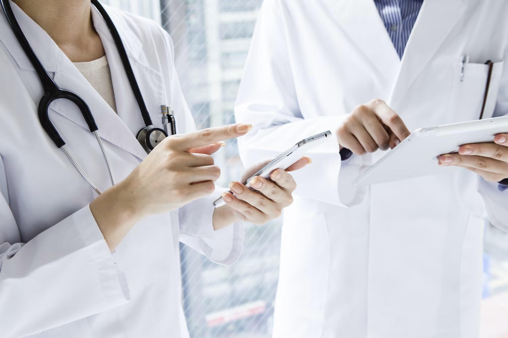 healthcare workers reviewing data on phones and tablets while standig in a hospital for healthcare industry