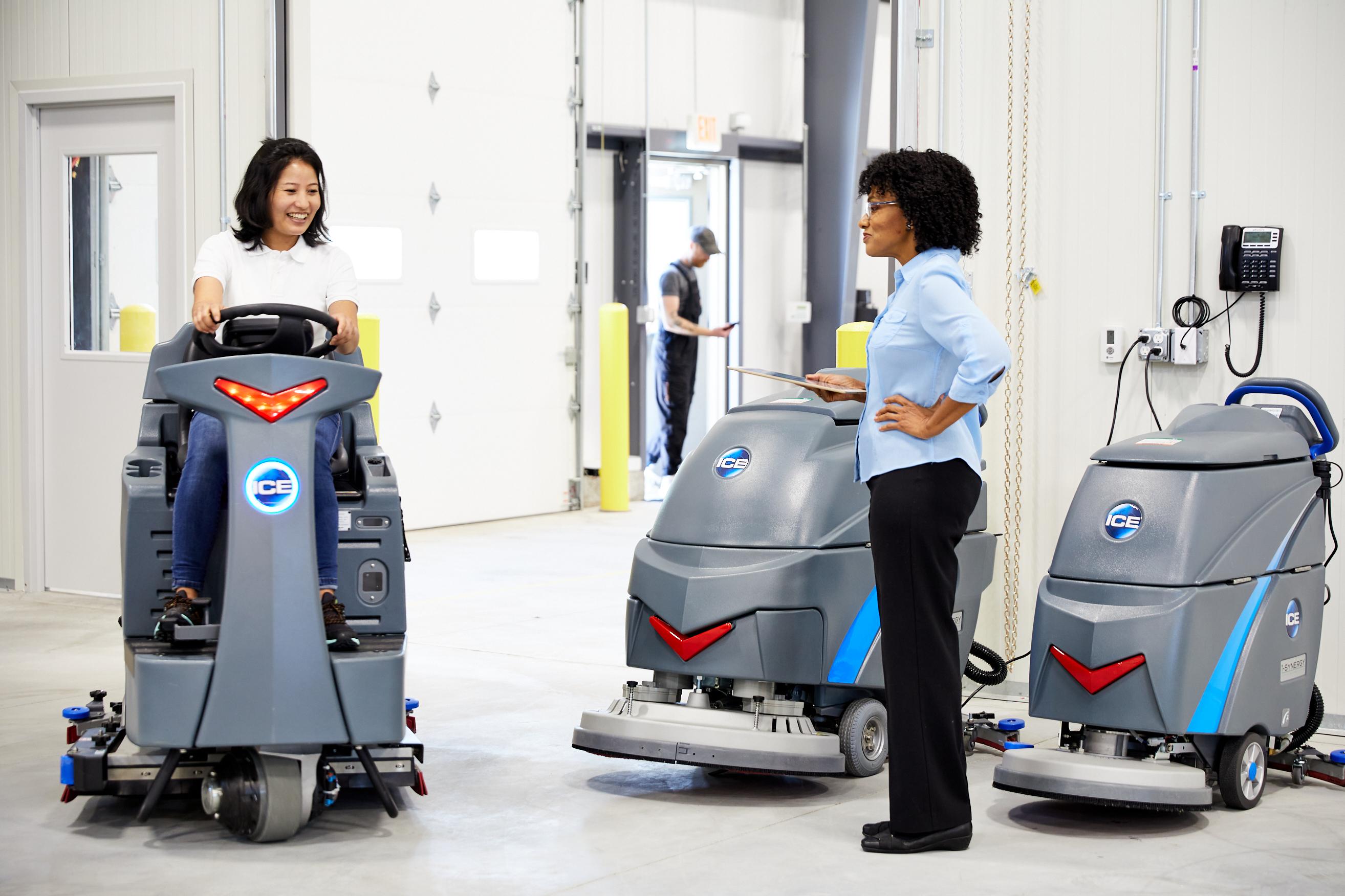 Two co-workers using ICE Cobotics intelligent cleaning equipment in manufacturing facility
