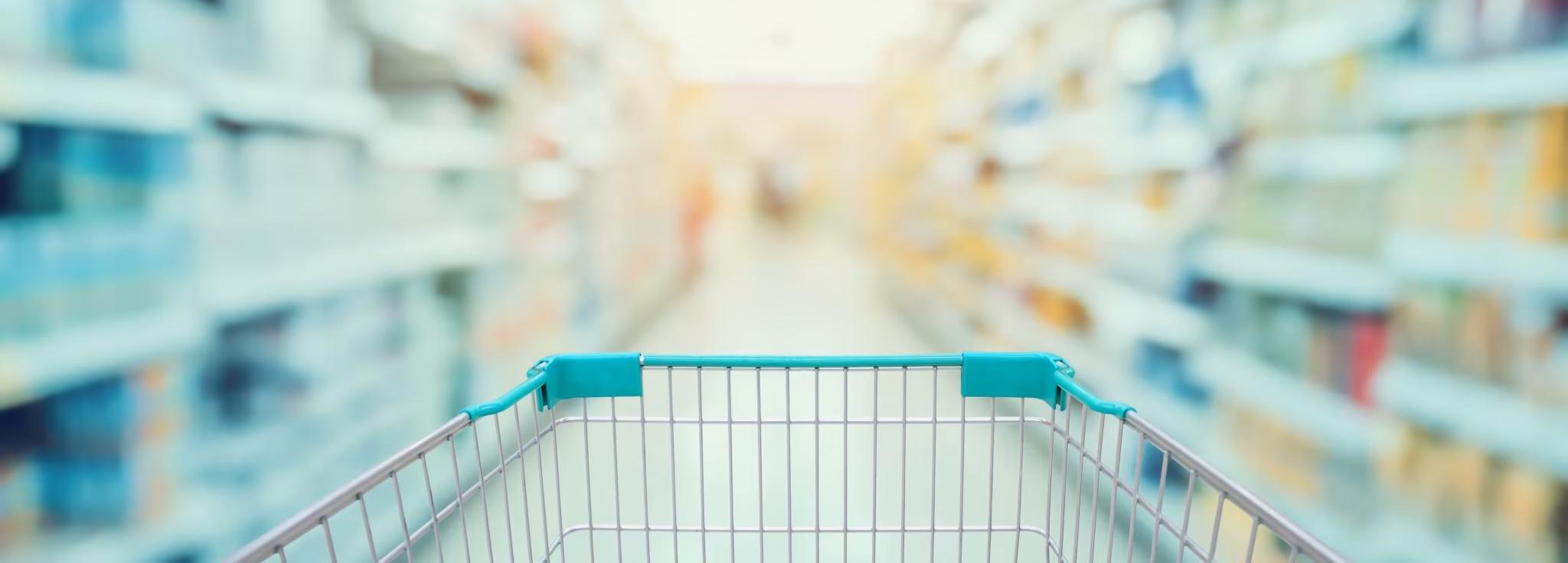 grocery retail store with blurred background and shopping cart going down grocery aisle